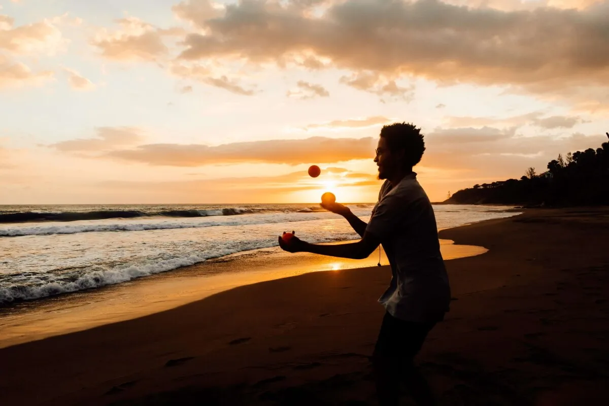 Silhouette of a person juggling on the beach at sunset