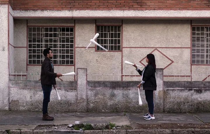 Two jugglers passing clubs to each other in the street